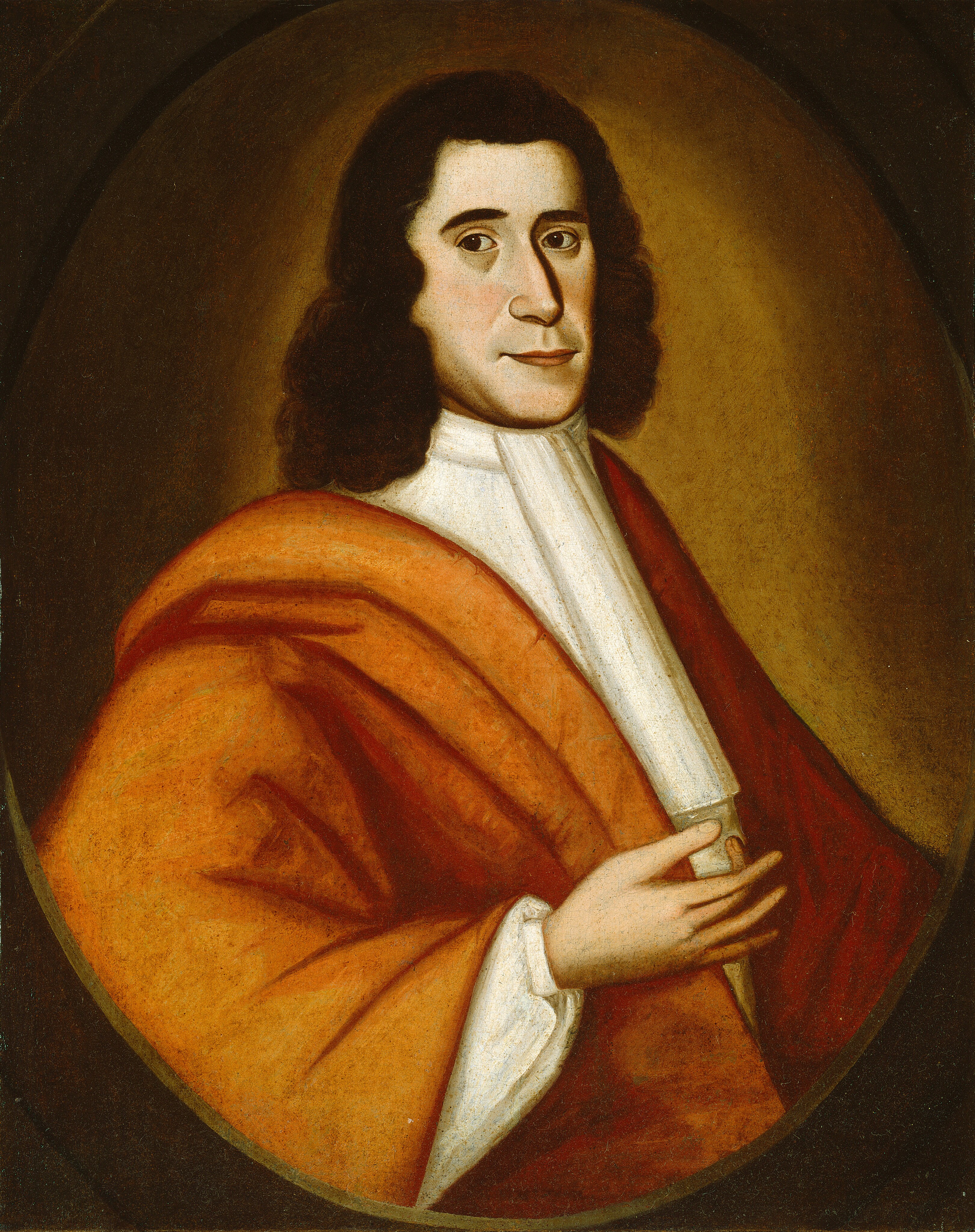 This image is a portrait of a person from the waist up. The individual is facing forward, slightly turned to their left, with their right hand placed on their chest. They have wavy, dark brown hair that falls just below their shoulders, slightly arched eyebrows, dark eyes, a straight nose, and a subtle smile. The person wears a white shirt with a high collar and an orange outer garment draped over their shoulder. The background is a simple, muted brown that darkens towards the edges, framing the person in an oval vignette effect.