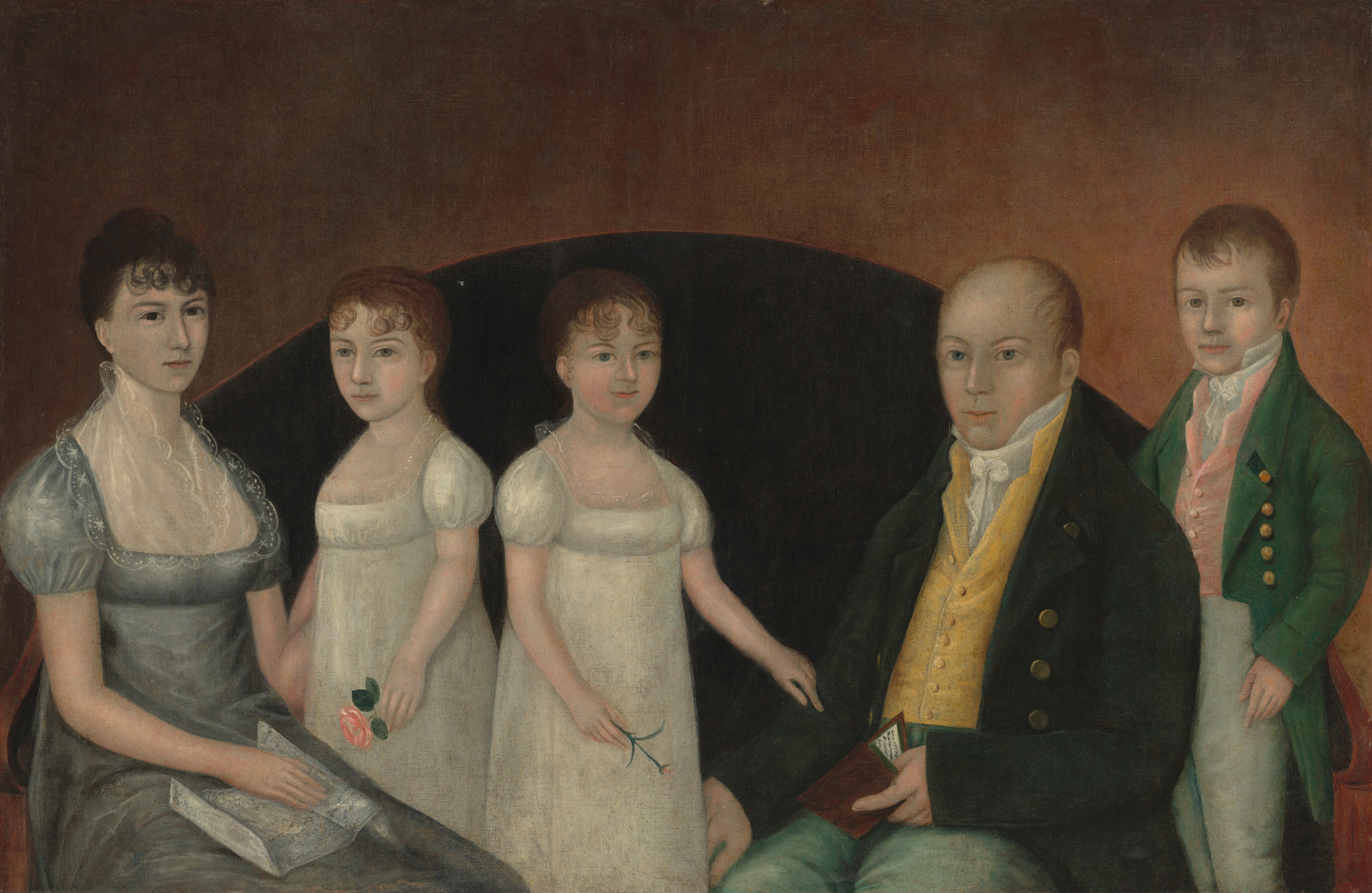 This painting looks like a family portrait with five people: two seated adults and three children. The person on the far left is a seated woman with dark hair styled up and short, curling bangs, wearing a gray dress with puffed sleeves and lace details at the neckline. She holds a folded piece of paper in her lap and has one arm around the girl next to her. On her right stand two young girls with curly reddish-brown hair tied back, both dressed in white dresses with puffed sleeves and lace around the necklines. The girl to the left holds a pink flower, while the other holds a small pink bud. On their right is a seated man with short reddish-brown hair, wearing a dark jacket over a yellow vest and a white cravat and green trousers, holding a small book partially open. Standing to the right, partially behind the man, is a young boy dressed in a green coat with gold buttons over a pink vest and white shirt. All five of the people have pale skin. Behind the family is a black semi-circle, and around that is a gradient of brown, darker at the top and lighter towards the bottom.