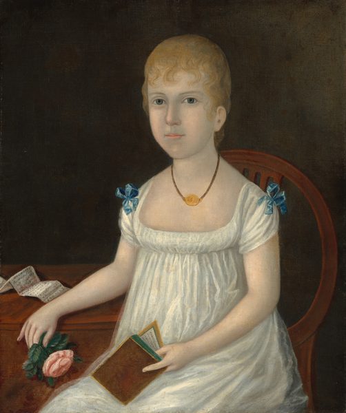 This painting shows a young woman seated on a wooden chair, seen from the knees up. Her body is slightly turned to the left, but her head is turned towards us. She has short, curly, blonde hair and a round face with a fair complexion. She has a straight nose, thin eyebrows, and thin pink lips in a neutral expression. She is wearing a white gown with a wide neckline, short sleeves, and blue bows on the shoulders, as well as a brown necklace with a circular golden pendant. In her left hand, she holds a small brown book with green edges, and her other hand rests on a brown table next to her, holding a pink rose. On the same table is a paper with several lines of indistinguishable text on it. The background is dark gray.