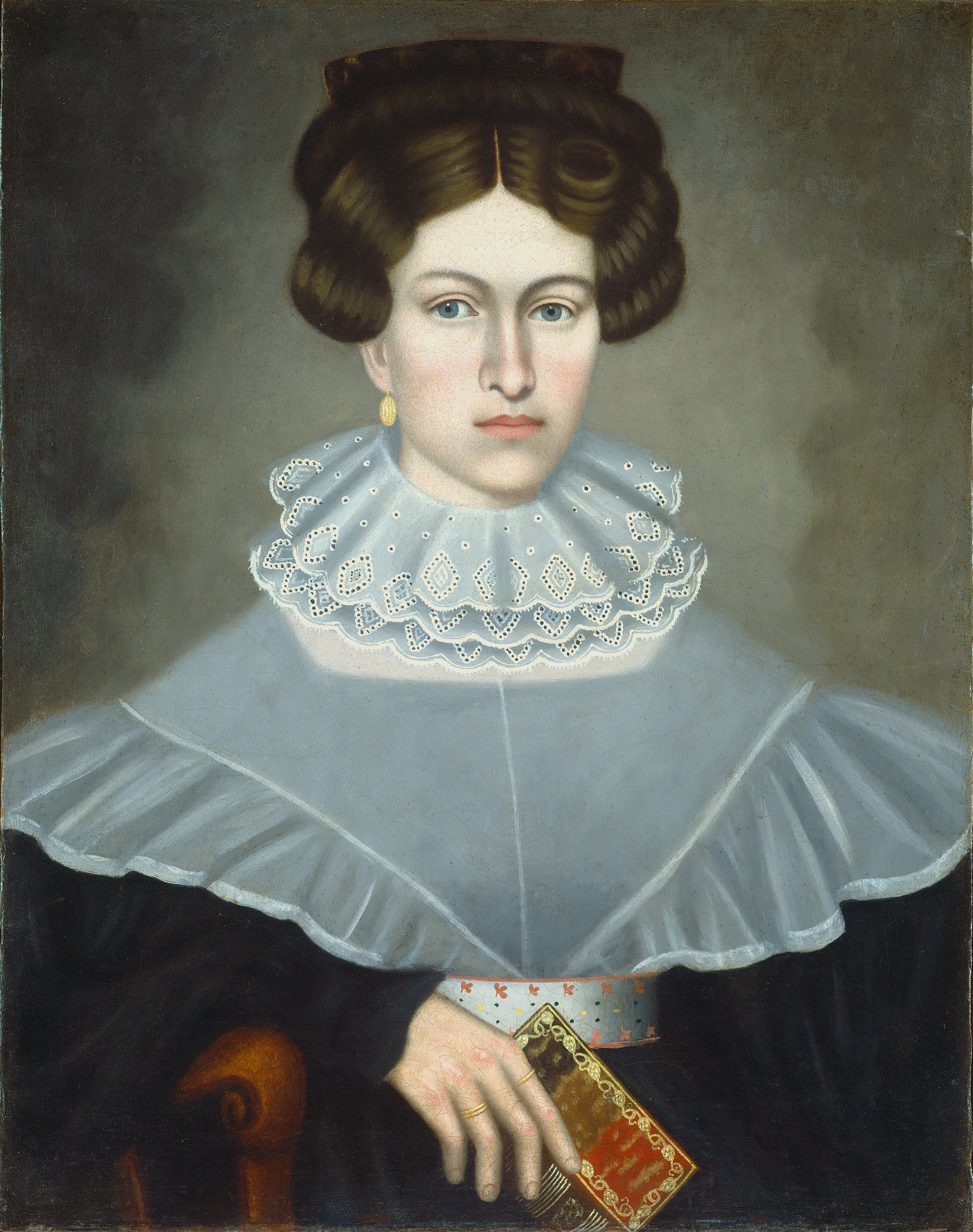 The image shows a woman portrait from the waist up. She is seated upright, holding a book in her left hand. She has blue eyes, dark brown hair styled with rolls and a braided crown, and wears elegant 19th-century clothing with a lace collar, a blue-gray garment, and gold earrings. The background is plain, and she is seated on a wooden chair.