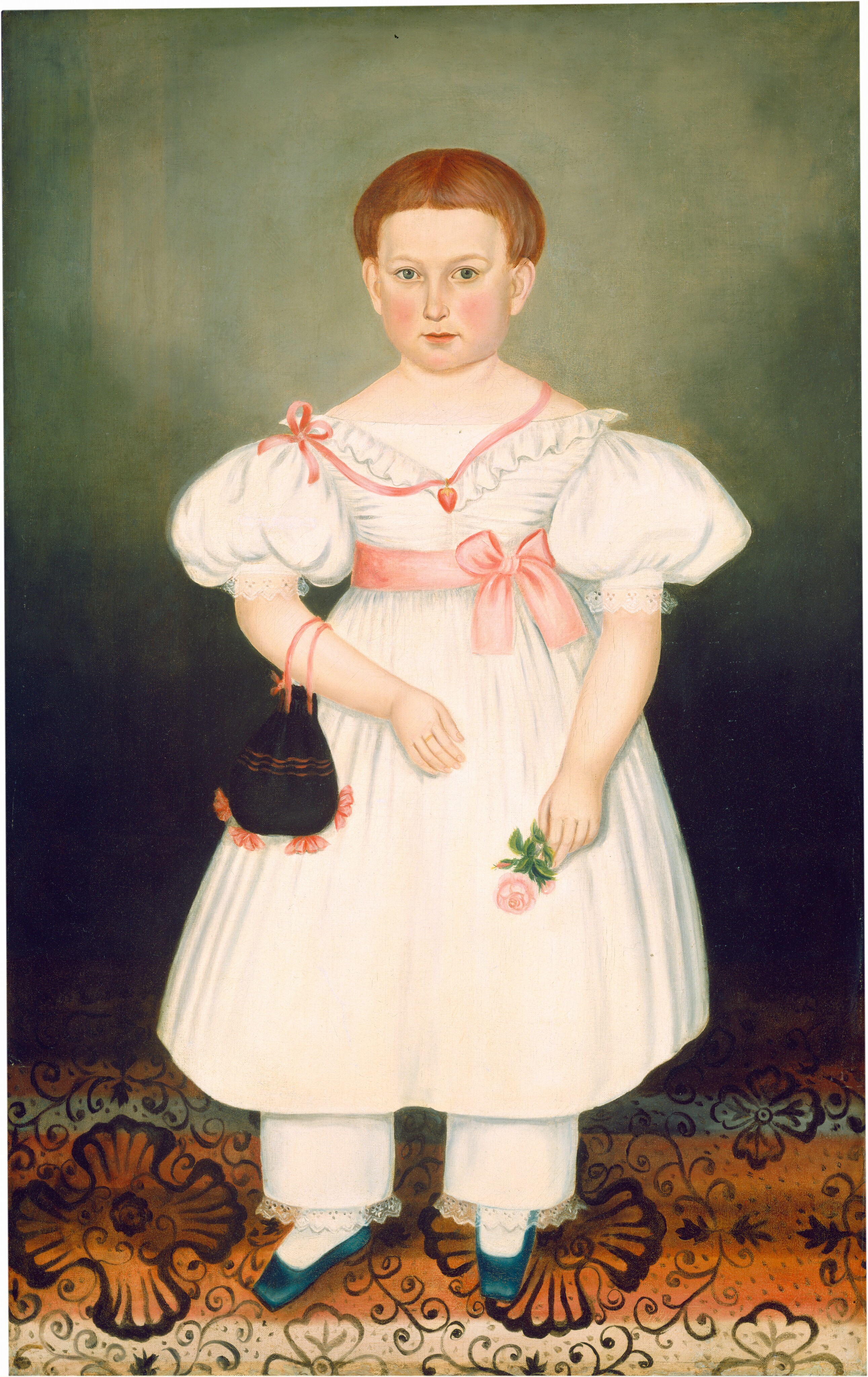 The image shows a child standing upright, facing forward. They have fair skin, rounded cheeks, short reddish-brown hair, and are wearing a white dress with lace details and a pink ribbon, white pants with lace trim, blue shoes, a red necklace and a heart-shaped pendant. They hold a light pink rose in their left hand and a small black drawstring purse with red accents in their right hand. The background is a gradient from dark green to light green, with a floral-patterned carpet in black, brown, and red on the floor.