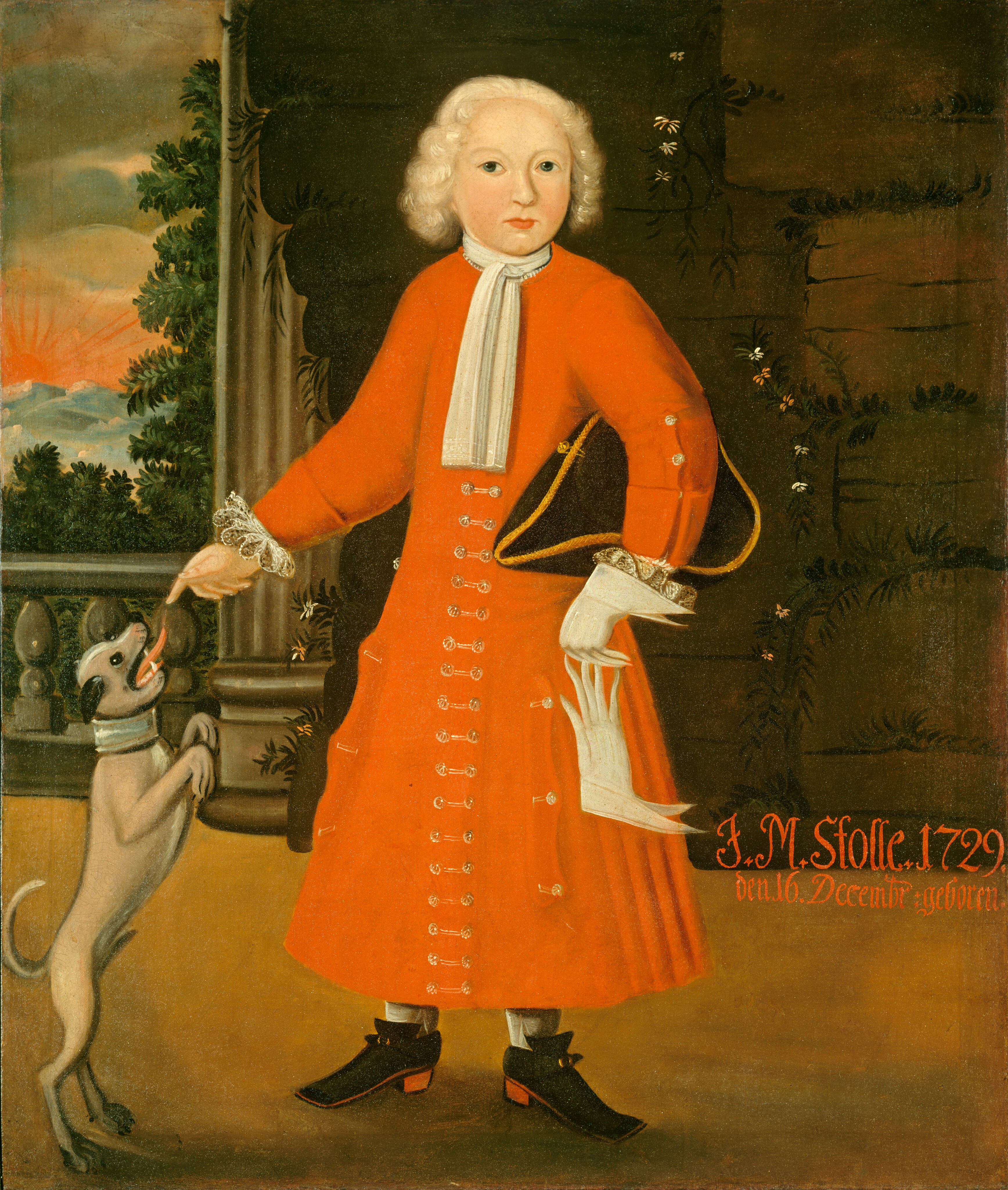 The image shows a young person standing and slightly turned to their right. They have light blonde, shoulder-length hair and a fair complexion. The person is dressed in a red overcoat with white accents and a white cravat, paired with black shoes. The individual is holding a scroll in their left hand and touching a small dog standing on its hind legs with their right hand. The background includes an archway or stone wall with plants growing on it, along with trees and a sunset or sunrise over mountains.