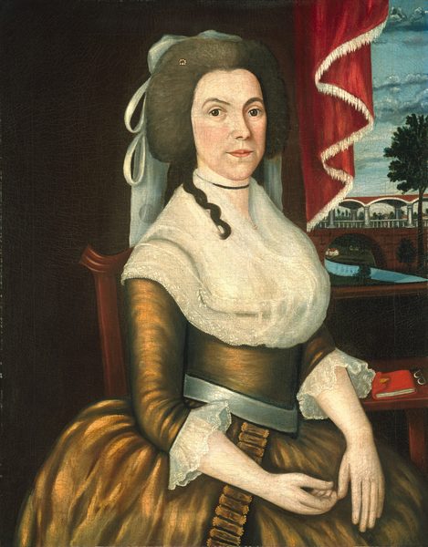 The image shows an upper-body portrait of a woman sitting in a three-quarter view, facing slightly to her left. She has delicate facial features, smooth complexion, arched eyebrows, and an expression that might suggest attentiveness. Her brunette hair is styled with curls on the sides and a hairpiece topped with a lace headdress. She wears a high-necked gown with long sleeves featuring lace detailing at the cuffs and a voluminous, dark brown skirt, along with a white shawl or fichu draped around her shoulders. Her left hand is visible resting on her lap, while the other hand is unseen. A bracelet or band is visible on her right wrist. The background features a red curtain with a white trim drawn to the side, revealing a scenic view of a bridged body of water and surrounding greenery, with a partly cloudy sky above.