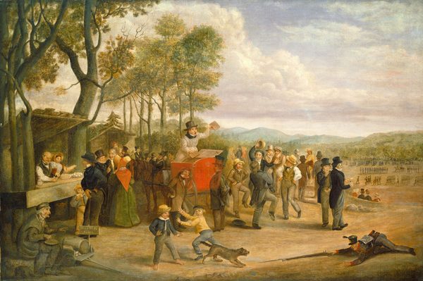 Approximately two dozen people gather around a man standing with his mouth wide open and holding up two objects in a scarlet-red structure on a horse-drawn cart in this horizontal painting. The people appear to all have pale skin and most are men. Near the center of the composition, the man in the cart wears a white robe over a black, high-collared garment and a tall charcoal-gray hat. A hatch on the red structure appears to be open, and he holds up what might be books or pamphlets. A ginger-brown horse stands behind him with its head bowed. In the crowd, the men wear black, brown, gray, dark blue, or olive-green clothing and hats. Two women are to the left. One wears a green gown with a pumpkin-orange shawl and a wide-brimmed bonnet. She faces away from us. She and two men talk near a stand where another man and woman sell food and drink. More people gather around a second stand or structure beyond this, and, in the lower left corner of the painting, a man with white hair and a hooked nose and chin sits by an open cart with a sign reading, “Bear O! Pi Aiggs.” A few men dance and others mill about to the right of the cart. Closer to us, one boy runs toward another as a soldier lies belly-down on the ground, holding a bayoneted rifle out toward a brown dog. The dog crouches with its mouth open. Beyond the dancers and onlookers, a field stretches back to wooded hills. In the field, more than a hundred people stand or march in lines. Lavender-tinged clouds pile up in the blue sky over the horizon, which comes about halfway up this composition.