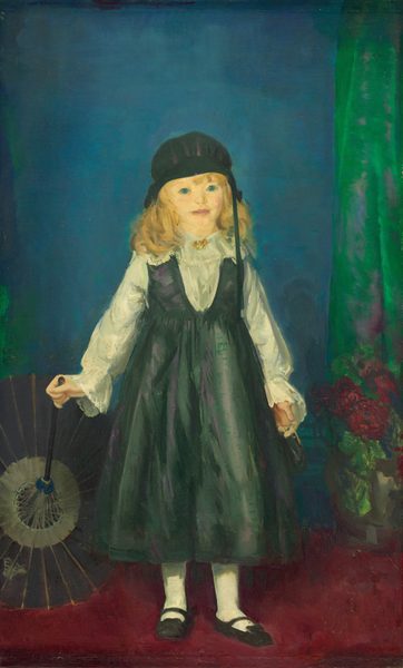 This painting shows a young girl standing and facing forward. She is holding an open, dark-colored parasol with one hand and a small, indistinct object with the other hand. She stands on a red carpet, and the open top of the parasol rests on the floor. The girl has pale yellow skin, bright blue eyes, and wavy blonde hair under a black cap. She is wearing a dark green pinafore over a white blouse with lace details, white stockings, and black shoes. In the background, there is a blue wall with a green curtain on the right side. A vase with red flowers is partially visible on the ground to the right.