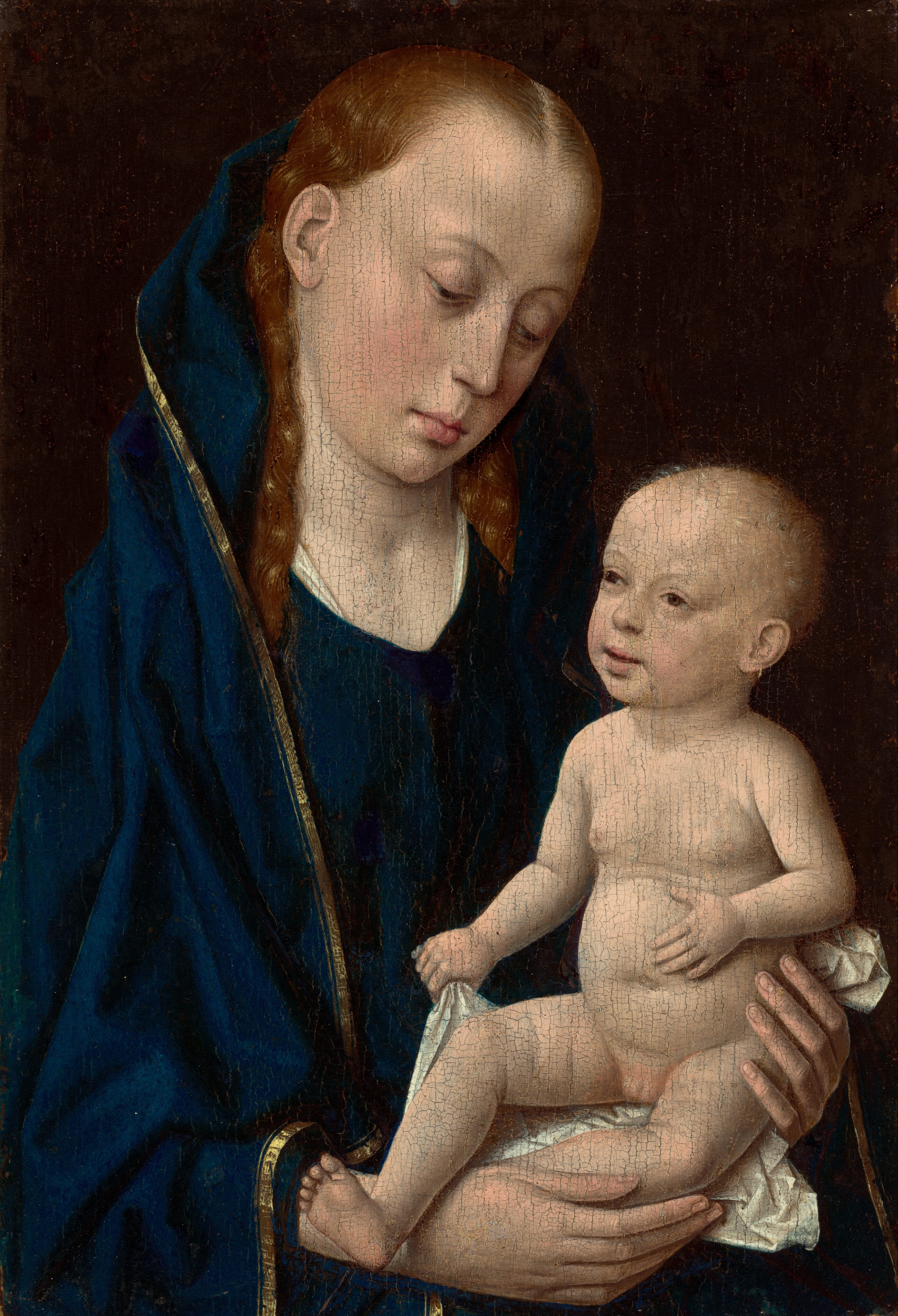 Shown from the waist up, a woman holds a nude infant in this vertical painting. Both have pale, peach-toned skin with brown eyes, faint eyebrows, and delicate features. The woman’s full, pink lips are closed, and she has a pointed chin. Her wavy, reddish-blond hair is parted in the middle and falls behind her shoulders. She wears a dark blue robe with a narrow gold border draped over her head and around her shoulders and body. She looks down at the child, to our right, which she holds in both long-fingered hands on a white cloth. The baby’s head is covered with a fine fuzz. He looks off to the left and grips the white cloth with the hand closer to the woman. His other hand rests on his round belly. The woman’s right hand wraps across one tiny leg, and the other foot stretches out over that wrist.  The background is dark brown, and cracking on the painting’s surface is visible throughout.