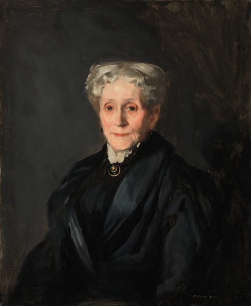 The painting is of an older woman from the waist up, her body slightly turned to the left and her head facing us. She has pale skin with soft lines, rosy cheeks, deep-set eyes, thin eyebrows, and thin red lips in a neutral expression. Her hair is short and wavy, colored in a soft grayish white. She is wearing a dark dress, contrasting with a light, frilly collar at the neck, where a round, dark pendant set in gold rests. The background is a dark, muted color. The brushstrokes in the painting are visible.