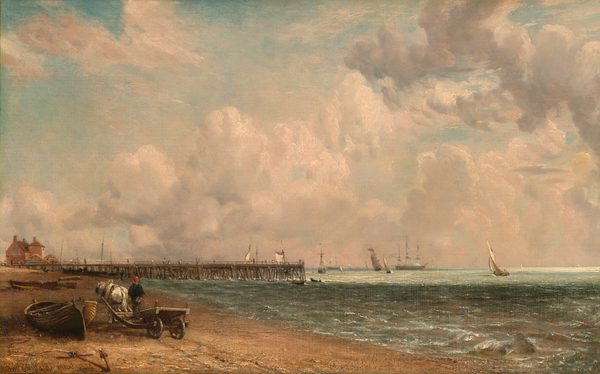 This painting shows a seaside view with a low horizon.  A sandy beach is on the left, with ships and sailboats sailing on the water in the distance on the right. From the beach on the left, a pier in the distance extends into the water, with people walking on it. There is a pink building on the beach near the end of the pier. Closer to us, near the bottom left corner, is a white horse tied to a cart with a person standing on it. The horse and person both face away from us, heading towards the pier. They are passing by a small wooden boat that lies in the sand on their left, connected by a rope to a dark red anchor submerged in the sand. The brushstrokes are smooth and detailed in the sky and sea. The color palette is dominated by pastel tones of beige, blue, and grey. The water is greenish-blue, with darker areas of shadow and light areas in the distance. The sky is blue, full of puffy white clouds that are tinged with light pink.