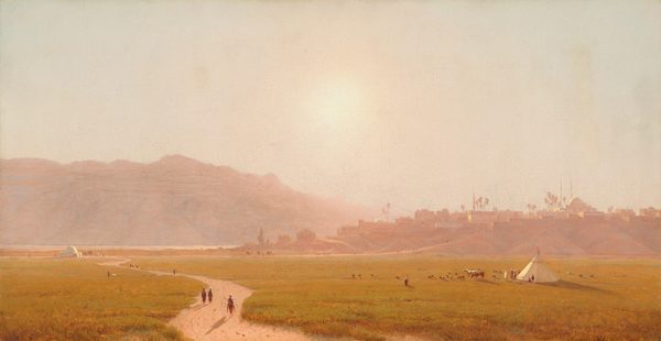 A dirt path winds through a field of gold-green grass back to a town built on low hills in this horizontal, densely hazy landscape painting. Several minuscule people walk on the path and at least one person rides a horse. More people are gathered by a domed, white structure in the distance, where the winding path meets a straighter road leading up into the town near the left edge of the canvas. At least six people sit or stand near a conical white tepee to the right, in the lower quadrant. Two horses and about two dozen smaller animals graze nearby. In the town, the cluster of low, flat-topped buildings, the one domed building with two slender minarets, and palm trees are painted in tones of muted mauve pink and peach. The sun is painted as a hot blaze of light low in the washed-out sky over rocky mountains, which stretch across the left half of the composition. The artist signed and dated the painting with angular red letters in the lower right corner, “S.R. Gifford 1874.”