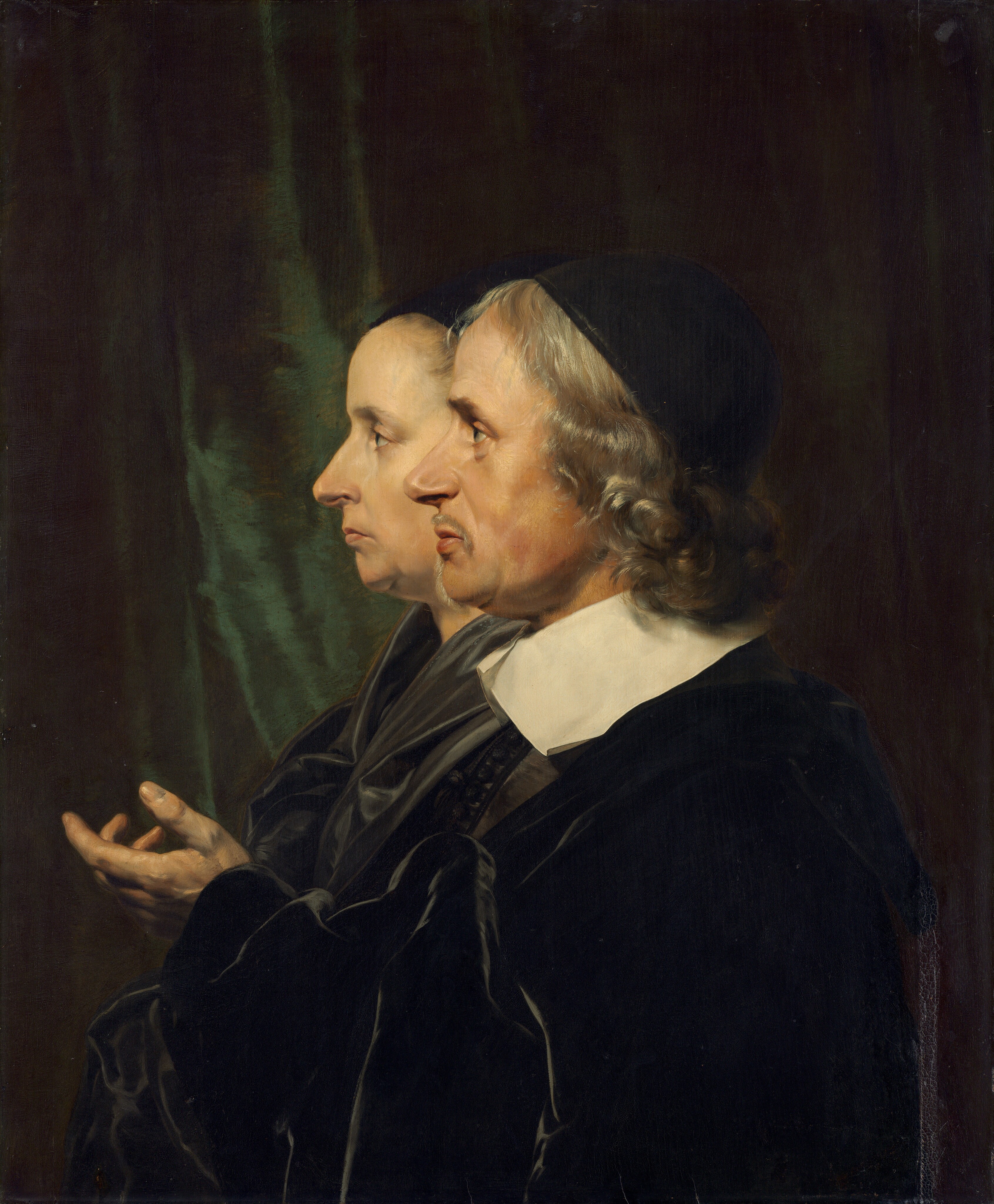 Shown from the shoulders up, a man and woman face our left in profile against a shadowy, dark green curtain in this vertical portrait painting. They both look steadily to our left, they and have pale skin and wear black. The man is closer to us so he overlaps the woman, whose profile is shifted to our left. A black cap sits on the man's curly, silver, shoulder-length hair. He has a slight double chin and soft jowls. A thin mustache curves over his upper lip, and a line of hair runs down his chin as a narrow beard. A broad, flat, white collar lies across his shoulders over a velvety black coat. He lifts his left hand, closer to us, in front of his chest with the fingers curled gently inward. The woman also has a double chin and soft jowls. Her thin lips are closed and downturned. Her hair is pulled back under a black covering, and her black garment has a sheen, suggesting satin.