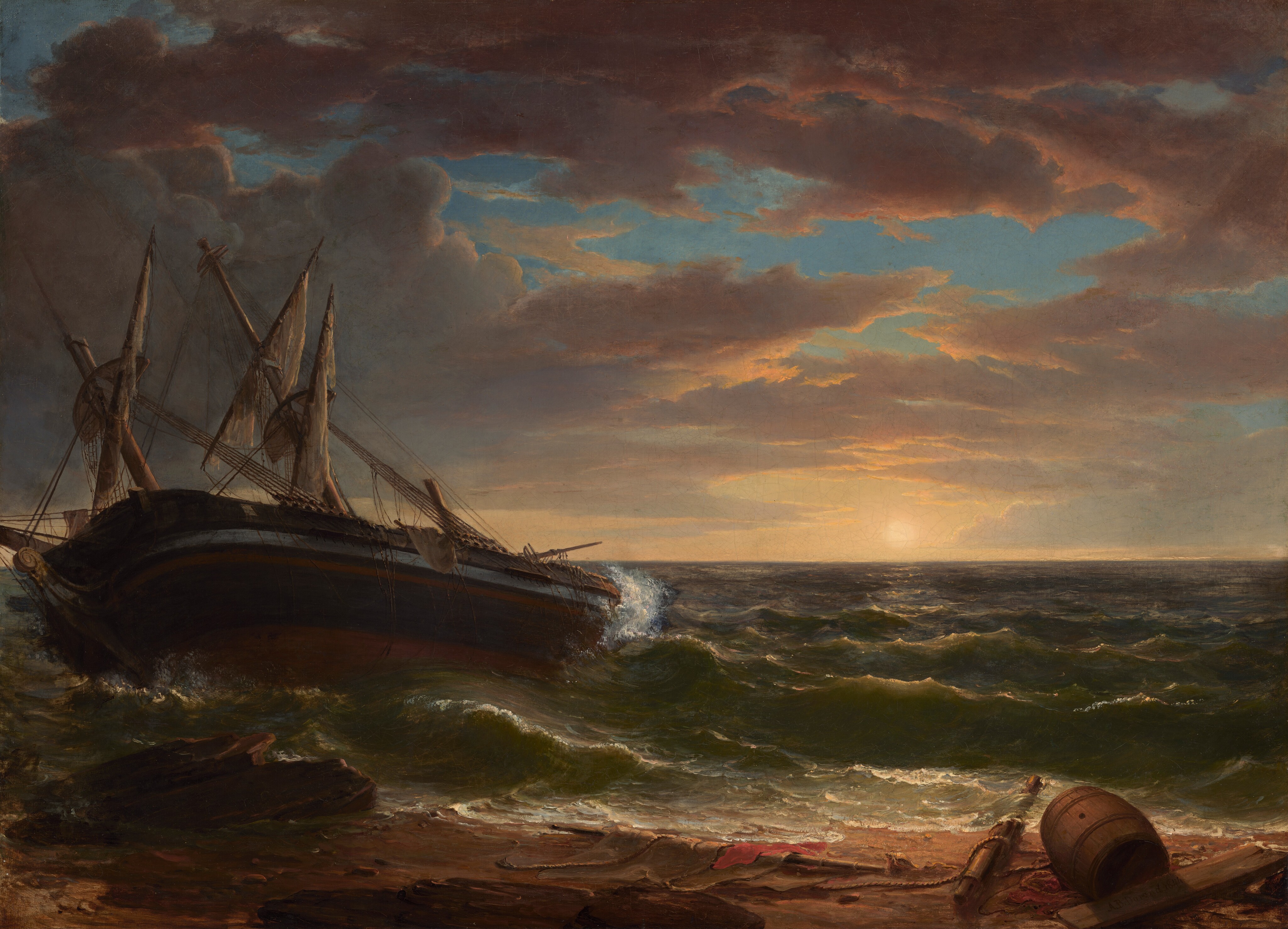 A large, dark sailing ship to our left is stranded near the shore, angled dramatically away from us, in choppy waves under a periwinkle-blue sky streaked with gray and copper-colored clouds in this horizontal painting. Two tall masts on the ship angle steeply away, showing that the boat nearly lies on its side. The third mast is broken. The rigging is askew and the sails are tattered. Light catches a steel-blue band around the deck. Broken pieces of masts, swaths of limp, gray sails, thick rope, and a wooden barrel on its side are scattered along the beach in front of us. Bottle-green waves break gently on the beach, but white foam kicks up around the hull. Low, bronze-brown rocks jut outwards from the beach to our left. To our right, a pale, yellow sun glows hazily just over the horizon, which comes about a third of the way up the canvas. The dark gray clouds brighten to pale yellow, lavender purple, and mauve pink along the edges and near the sun. The artist signed and dated the painting as if he had inscribed a board lying in the shadow cast by the barrel in the lower right corner: “A.B.Durand 1884.”