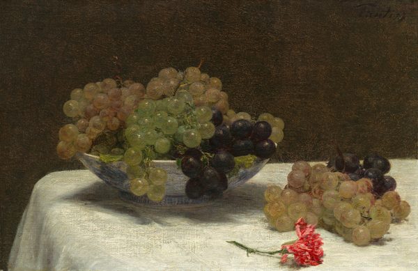 A blue and white bowl overflowing with grapes, two loose bunches of grapes, and a vivid pink carnation lie on a white tablecloth against a dark brown background in this still life painting. The grapes vary from bright, translucent green, green with pink tones, and dark purple. The bowl is to the left of center, and it and the grapes it holds take up most of the left two-thirds of the composition. A bunch of grapes shaded green and pink and a bunch of dark, almost black grapes sits to the right of the bowl, and the short-stemmed carnation lies between us and those loose bunches. The table continues off the right edge of the canvas and comes to an end just short of the left edge. The artist signed the painting in the top right corner, “Fantin.”
