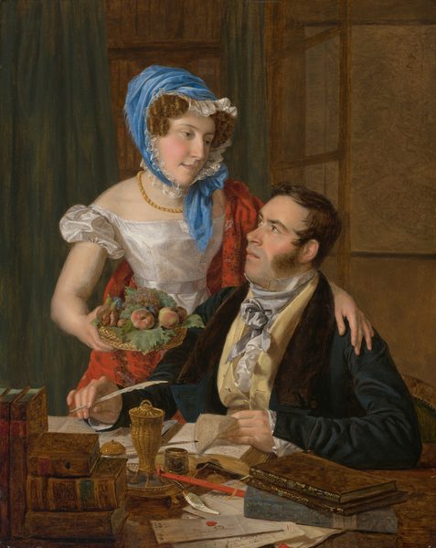 This painting shows two people. A woman is leaning over a seated man from the left, with one arm around his shoulder and holding a basket of fruit in her other hand. Her head is slightly tilted as she looks down at the man. She has curly brown hair partially covered by a blue headscarf with a lace border. She wears a white dress with puffed sleeves and a gold necklace, as well as a red cloth draped over one shoulder and down her back. The man is seated at a desk with his body angled slightly to the left, looking upwards toward the woman. He has dark brown sideburns and dark hair. He is dressed in a dark coat with a light-colored waistcoat and a light gray cravat. Both people have pale skin. On the desk are several books, papers, and writing implements, including ink and a wax seal. The man is holding a quill pen in one hand and turning the page of a book with the other. The background features pale greenish drapery and a wooden paneled wall with what looks like a map hanging on the right.