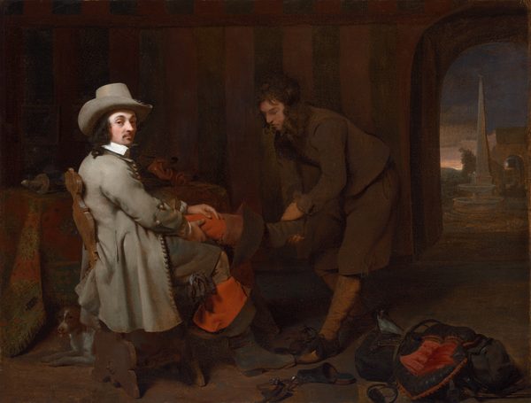 This is a painting of two individuals in a dimly lit room. One person on the left is seated; they are richly dressed in a gray hat and long gray coat, and they look directly toward us. They have pale skin, dark hair, and a dark mustache. They are being assisted by another person on the right who helps them take off their boots. The assistant also appears to have light skin and dark hair, and they wear simple brown clothes. They are in shadow, while the seated person’s face is brightly lit. The dark room features a table with an ornate cloth, a small dog under a chair, scattered shoes, fabric, and an archway showing a glimpse of an exterior scene with a fountain and obelisk against a twilight sky.