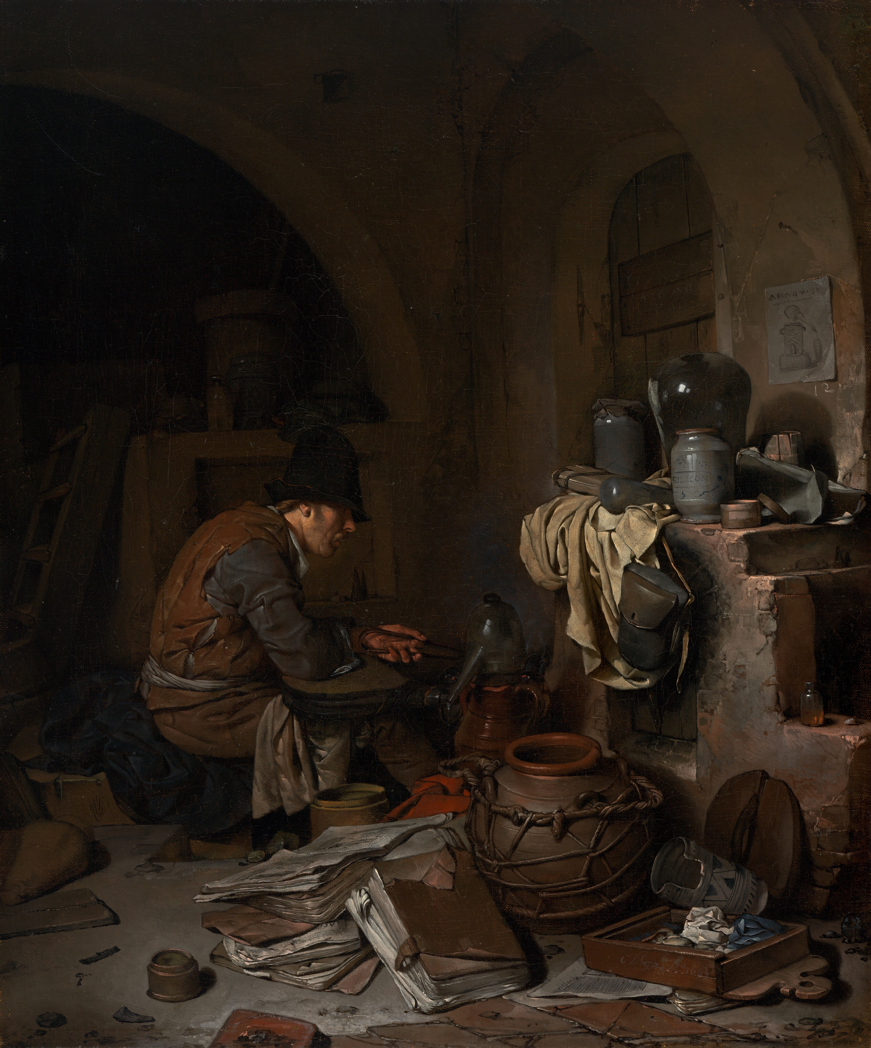 A light-skinned man sitting near an oven is surrounded by papers and vessels, all within a shadowy room in this vertical painting. The scene is dominated by chocolate and clay brown, black, slate blue, and shades of gray. The man sits facing our right in profile near the center of the painting. He wears a tall black cap that shadows his eyes and a rust-brown sleeveless garment like a vest over dark, steel-gray, long sleeves. Cream-white fabric tied around his waist could be an apron, and more white fabric drapes over his knees. Brown hair is visible behind his ear, he has a mustache, and his lips are parted as he looks down toward the instruments in front of him. He is hunched over, the elbow closer to us on what might be a flattened bellows, and he holds tongs in his left hand. The vessel in front of him could be made from pewter or glass, and it has a high, curved top and a long spout angled downward. Other pots and a red cloth are jumbled with large, leather-covered folios like thick folders of papers on the floor close to us. More papers, pots, and containers sit on a wide ledge over the open fireplace or oven to our right. A piece of parchment-white cloth hangs down the front of the oven next to a leather knapsack that hangs from the mantle. The top zone of the painting is deep in shadow but there seems to be an arched window or door covered with a wooden shutter to our right, behind the oven. A piece of paper affixed to the wall near the opening shows a vessel like the long-spouted vessel in front of the man. A shallow wooden box near the lower right corner seems to be filled with crumpled paper or cloth. The artist signed and dated the front face of the box with light letters: “C. Bega Ao. 1663.”