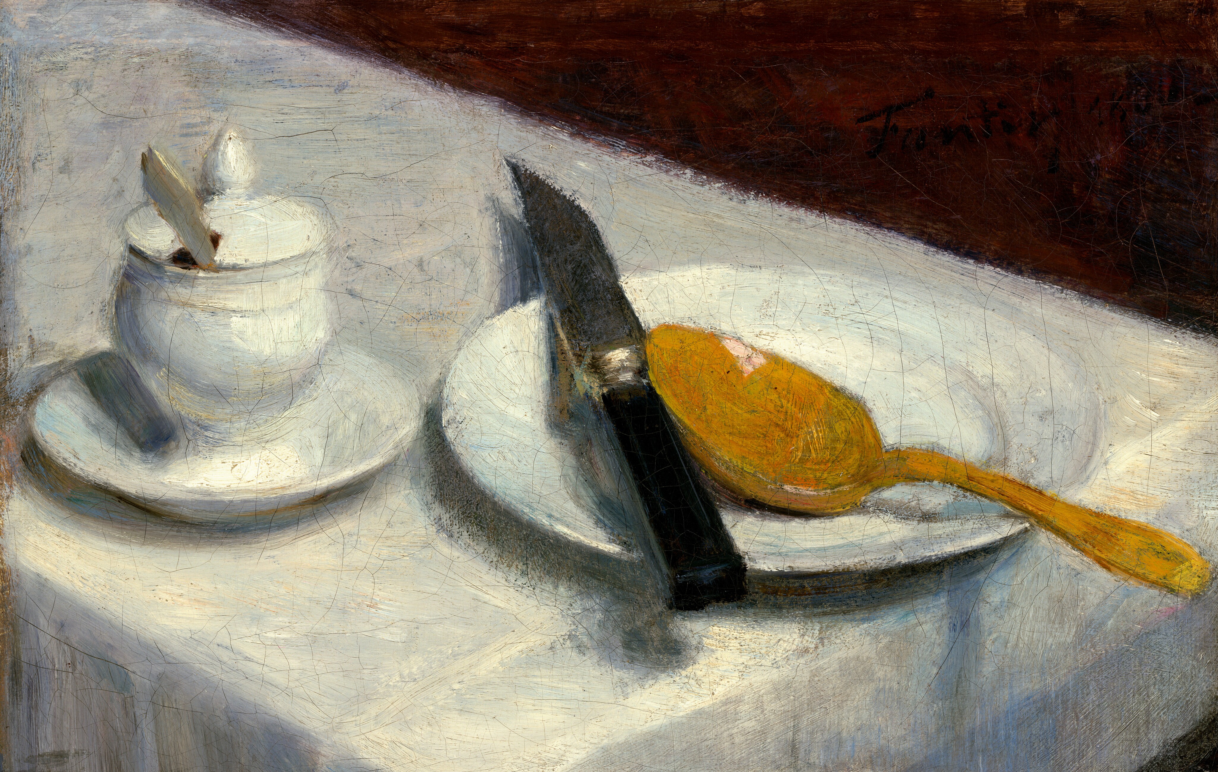 We look down at the end of a narrow table at a white plate, pot, knife, and spoon set on the white tablecloth in this horizontal still life painting. The table angles from the top left down into the bottom right of the composition, and the corners of the table itself are cut off by the right and bottom edges of the canvas. At the left, a white ceramic vessel with a lid topped by a teardrop-shaped knob sits on a white saucer. The lid is notched and the handle of a utensil sticks out. To the right, a round white plate rests partly off the edge of the table. On the plate is a golden-yellow spoon positioned with its handle extending to the lower right. A black-handled knife lies across the rims of the plate, its dark blade angled upright and casting a long shadow behind it. The triangular slice of background above the tablecloth is a deep reddish brown. The brushstrokes are visible throughout the painting, and the surface has fine cracks.