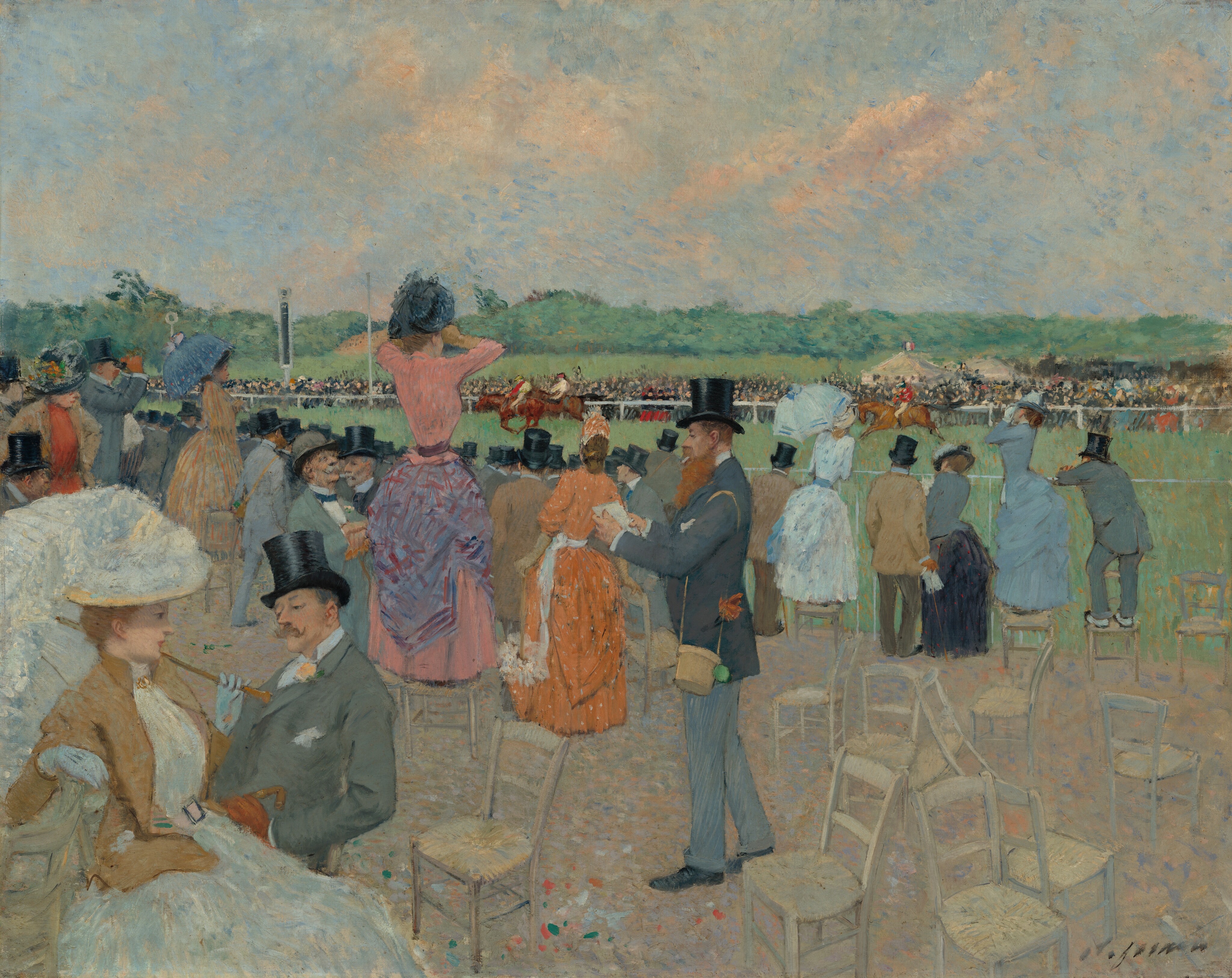 This painting shows a horse racing event with a crowd of spectators. Close to us, people stand or sit on chairs, most with their backs turned to us, facing the race. Some people stand on the light brown chairs for a better view. The women wear long, colorful dresses and hold parasols, while the men wear suit jackets in shades of gray with black top hats. Behind the crowd, towards the center of the painting, is a long strip of green grass where riders on horseback race towards the left, visible over the heads of spectators. Across from us, on the other side of the green expanse, another crowd of onlookers is gathered, along with a few cream-colored tents. Beyond that is more green grass and darker green trees. The sky above is light blue with soft clouds in shades of cream and peach.