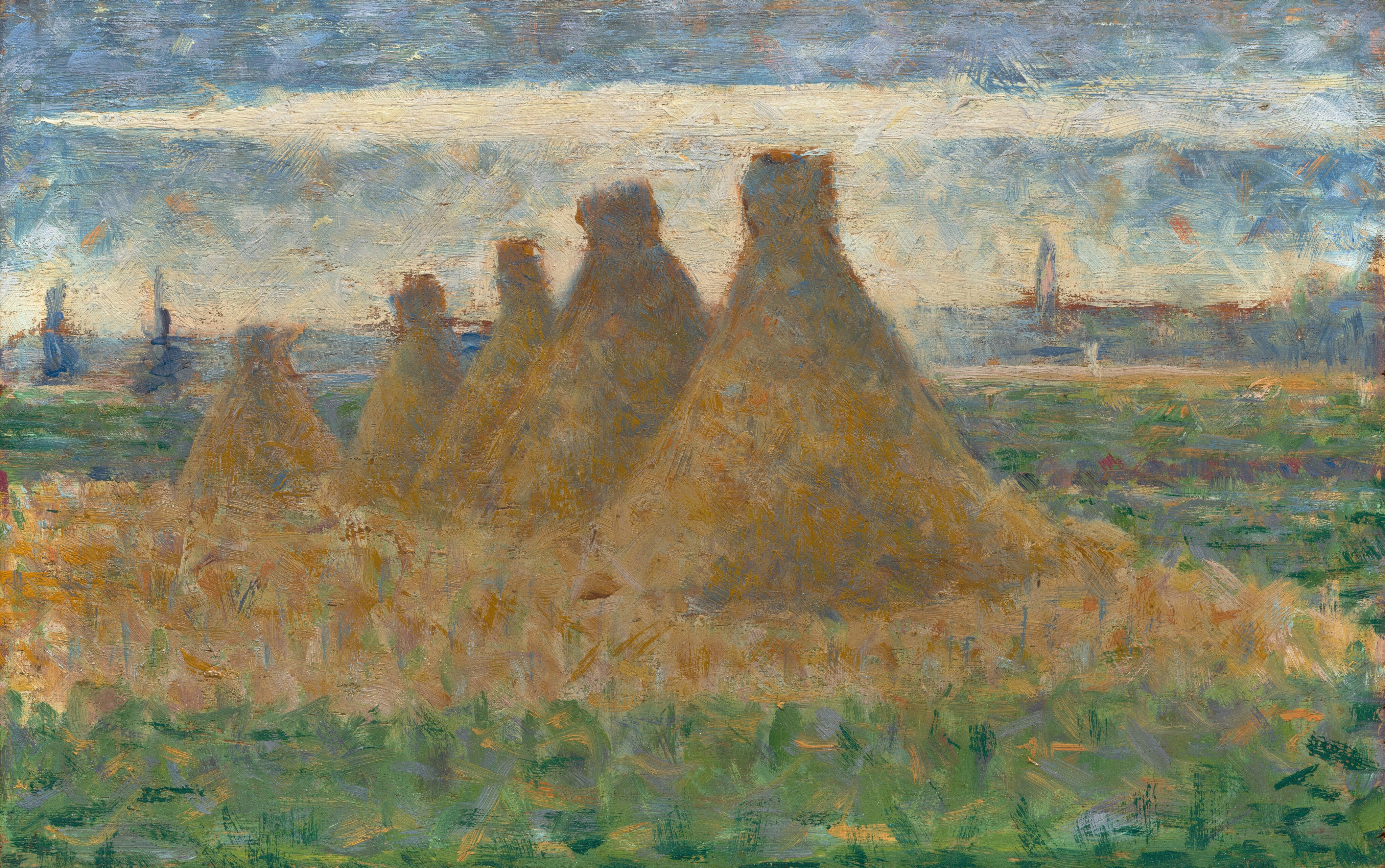 This painting depicts a landscape with several haystacks in the center, arranged in a line that cuts diagonally across a green field from left to right. The five large golden-brown haystacks are shaped like tall cones and are surrounded by more golden hay on the ground beneath them. The rest of the field is mostly green, with patches of yellow, purple, and light blue. The sky above the field is light blue, with long horizontal strips of white clouds. At the horizon is a line of purple and dark blue shapes, suggesting faraway trees, or perhaps low buildings. The brushstrokes are short and textured, making the landscape appear blurred.