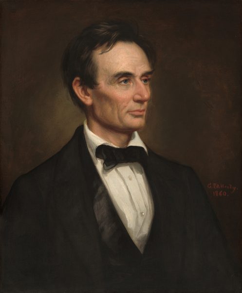 The head and shoulders of a cleanshaven, light-skinned man with black hair and a lined face is shown against a dark background in this vertical portrait. His body is angled to our right and he looks in that direction with blue-gray eyes under black brows. His hair is combed loosely back from his face but one lock falls onto his forehead, and it curls around the ear we can see. His prominent cheekbones are lightly flushed over hollow cheeks, which create noticeable shadows. He has a long nose, and his thin pink lips are closed. His forehead, the corners of his eyes, and the areas around his mouth and chin are lined with wrinkles. His black suit jacket has wide rounded lapels over a white buttoned shirt. The collar folds over a black bow tie and the two buttons visible on this shirt shine. Next to his left shoulder, on our right, the artist signed and dated the work with red paint: “G.P.A. Healy 1860.”