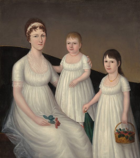 A woman and two children wear nearly matching white dresses in this vertical portrait. All three have pale skin, and they look out at us. Their floor length, short-sleeved, scoop-necked dresses are made with what looks like light, tulle-like fabric gathered just below the bust. The woman sits to our left on a dark sofa. The back of the couch curves up over her shoulders and down to our right, and off the painting. The top edge of the sofa has nail-head trim, and the wall behind it is elephant gray. The woman’s curling brown hair is pulled back behind a white headband. She has gray eyes, and her pink lips are closed. She holds a sprig of strawberries with her right hand, which rests in her lap. Her left arm, on our right, wraps around the younger child, who stands on the sofa at the center of the composition. The child has blond hair and light brown eyes, and wears a delicate, coral bead necklace. To our right, the older child stands in front of the couch. Her black hair is brushed back from her face except for bangs sweeping across her forehead. She has dark brown eyes and wears a gold-colored necklace. The older girl holds a basket of strawberries with her left hand, and rests her other hand on the pointed end of a parasol, which is tucked behind her body to our left.