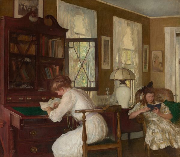 A young woman writes at a desk and a teenage girl reads a book in an armchair in an opulent room in this nearly square painting. Both women have rosy, peach-colored skin and honey-brown hair. To our left, the woman is shown from the knees up as she sits at a tall, mahogany-red, secretary desk. The desk has an emerald-green, tilted writing surface and two shelves packed with books and covered by glass doors, one of which is open. The desk has brass pulls on the drawers under and behind the writing surface, and the cabinet is topped with two curling scrolls to create a triangular pediment. The woman bends over her paper, facing our left in profile as she leans over and looks down at her writing. Her hair is loosely rolled up and pinned in place. She wears a white dress with ruffled, elbow-length sleeves and a lilac-purple sash. Golden chains hang from her neck almost to her lap, and a gold bracelet encircles her wrist. To our right and near the back corner of the room, the girl sits in a high-backed, wicker armchair. She hooks her right elbow, to our left, over the arm of the chair and leans in that direction, with a green pillow tucked into to her other side. Her body faces us and she looks down at a blue book in her hands. She has a round face, a straight nose, and her lips are closed. The girl’s hair is half pulled up in a dark bow atop her head as the rest falls around her shoulders. Her dress is streaked with pale gray, white, and harvest yellow, and is tied at the waist. Between the women, a dark brown cabinet or table holds a glass decanter with a glass stopper and lamp with a shiny, bulbus, white base and an off-white, rounded shade. Warm sunlight pours in from the two tall windows framed with ruffled, silvery-white curtains that flank the table, between the women. Mottled moss green and butter yellow suggest trees outside. The jamb of a French door runs along the right edge of the painting, beyond the reading girl. Several framed pictures hang on the sage-green walls. The artist signed the painting in the lower right: “Tarbell.”
