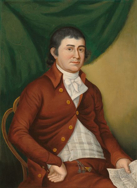 The image depicts the upper half of a man seated in a chair. He is posed slightly to the side, with his body angled to the right and his head turned towards the viewer. The man has a fair complexion, dark eyes, and short, dark, curly hair. He is wearing a reddish-brown coat with gold buttons, a white waistcoat, and a neatly tied white cravat. In his right hand, he holds a piece of paper with writing, while his left hand rests on his lap near a chain with small ornaments. The background shows a deep green drapery on one side and a plain, light beige wall on the other.
