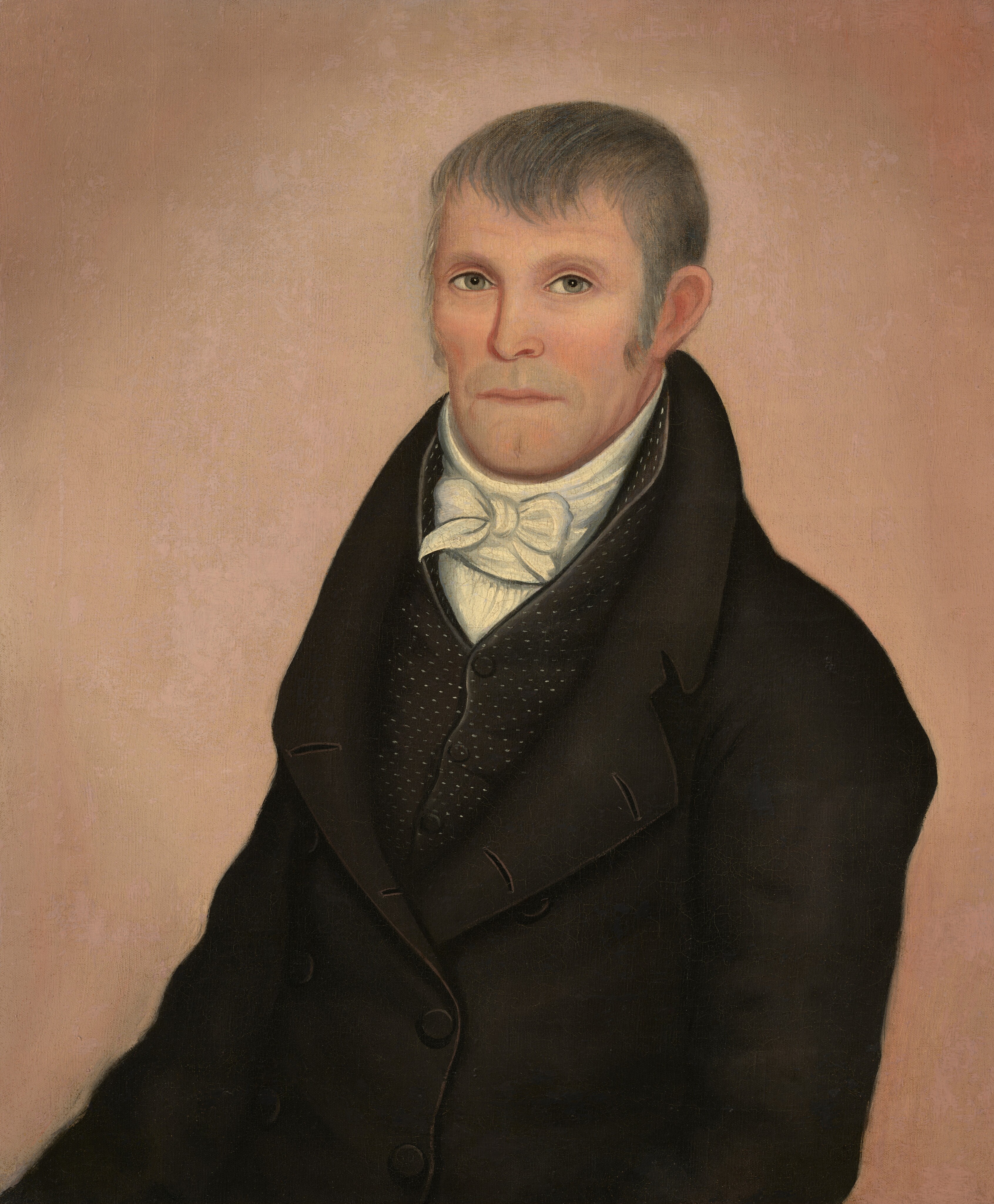 The image shows an upper-body portrait of a man depicted in a three-quarter view. He is seated upright, looking directly at the viewer. The man has a solemn expression with a prominent chin, thin lips, and alert eyes. His hair is short and appears grey, combed to lay flat against his head. He is dressed in formal attire, consisting of a dark colored coat with large lapels, a white shirt, and an intricately tied white cravat. The background of the image is a simple, solid color, which is a soft peachy tone, providing no additional context or detail. The overall composition focuses on the subject with no visible jewelry or other objects present.