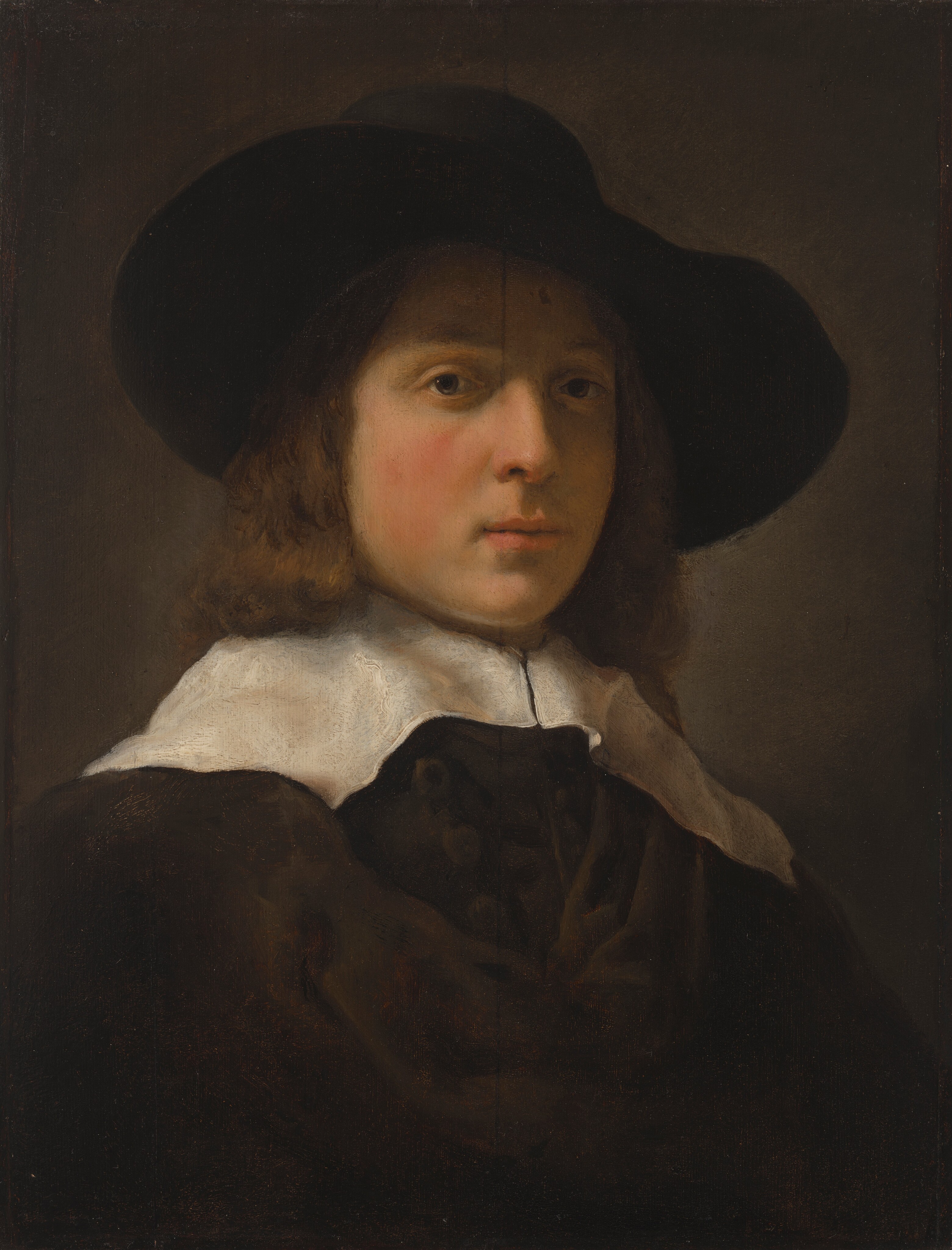 The image shows a person facing the viewer with facial features including fair skin, full lips, and brown eyes. The individual has shoulder-length brown, wavy hair and wears a large, round-brimmed black hat, dark attire, and a white lace collar. The background is a muted, dark brown color.