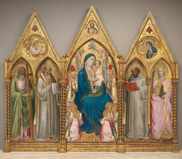 This altarpiece is made up of three panels, with a woman and baby sitting on a throne surrounded by winged angels at the center and flanked by a panel to either side that each shows two people standing under pointed arches. The background across all the panels is gold, and the top of each panel comes to a triangular point above. Spiraling columns frame and separate the sections. The people and angels have pale or deeply tanned skin, and wear robes in silvery-white, pale pink, celery green, crimson red, or pale yellow. They all have plate-like halos, which overlap for some of the angels around the throne. The floor across all three panels is patterned with gold against a burgundy-red background. The central panel shows a woman, Mary, wearing a lapis-blue robe, propping a standing baby up in her lap with both hands. The baby wraps one arm around her neck and grips the neckline of her dress with the other. The twelve angels around them look on from the sides or from small groups in the lower corners. Above the pointed arch over the throne, a bearded man is shown from the chest up in a shape of three lobes alternating with three points. That man faces us and holds up his right hand, to our left, with the first two fingers raised. He holds up an open book with Latin text with his other hand. In the panel to our left, two men with tan skin and gray hair and beards stand with their bodies angled toward the central panel. The man to our left holds a tall wooden cross and the man to our right holds up an open book with Latin text with one hand and a bundle of rods with the other. The gable above has a circle carved into its center. In that roundel is an angel inside a four-lobed quatrefoil, shown from the waist up facing our right. In the right panel, a man with tanned skin and a woman with pale skin stand under pointed arches. The man, to our left, holds and looks down at the pages of an open red book. To our right, the woman holds a palm frond in one hand and a closed green book in the other, and she stands in the circle of a wooden wheel lined with black spikes. The roundel above the pair shows a woman and a dove inside a four-lobed quatrefoil. Inscriptions appear with gold letters against a gold background across the bottom of each panel, so are difficult to make out. The panel to our left reads, “S. ANDREAS AP L U S; S. BENEDICTUS ABBAS.” Under the central panel, text reads, “AVE MARIA GRATIA PNELA DOMINUS.” The third panel reads, “S. BERNARDUS DOCTOR; S. K TERINA VIRGO.” Latin in the two books held outward is also legible. The book in the leftmost panel reads, “AUSCU LTA.O FILI.PR ECEPTA .MAGIS RI.ET.IN CLINA.AUREM CORDIS.T UI A MONITIONE M.PII.PA TRIS.LI BENTE R.EXCIP E.ET.EF.” In the central panel, the Latin inscription reads, “EGO SUM A O PRINCI PIU FINIS EGO SUM VI A. VERITAS VITA.”