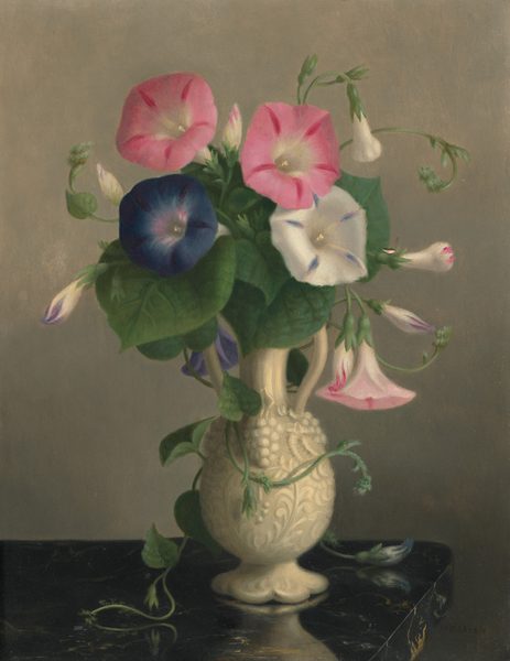 This painting depicts a decorated white vase filled with morning glory flowers. The blooms range in color from pink and white to a deep bluish-purple. Wide green leaves surround the flowers, and green tendrils cascade over the side of the vase, which has two handles around a thin neck and a body decorated with white carvings of flowers and fruit. The vase sits on a dark, reflective surface with hints of gold marbling. The wall in the background is a light gray color.