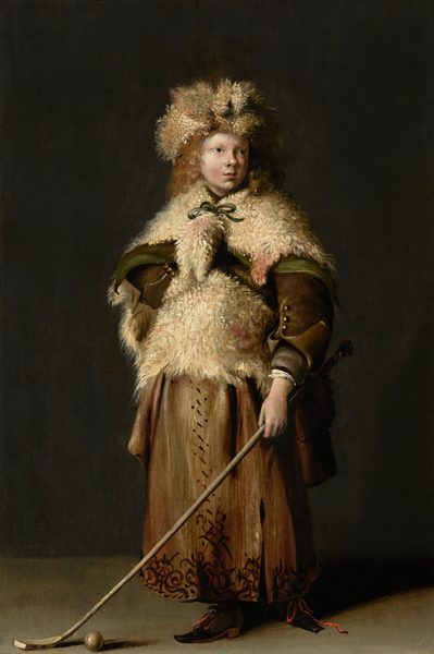 This painting depicts a person from head to toe, standing upright and looking off to the right. The person has a round face with fair skin and slightly flushed cheeks. Their long hair is curly and blond, peeking out from underneath a fluffy, off-white fur hat. They are dressed in a voluminous cream coat with a thick, fur-like texture, tied with a green ribbon at their neck. Their coat and hat have hints of brown and rosy pink among the light tufts. Underneath the fur coat appears to be a green cloak and a thick brown jacket, and they wear a long, decorated brown skirt with dark brown patterns down the front and around the hem. Below the skirt, pointed black shoes with red laces are visible. In their left arm, the figure holds a long stick with a hooked end next to a small ball near their feet. Their other hand rests on their hip. The floor is light gray, and the space behind them is dark gray.