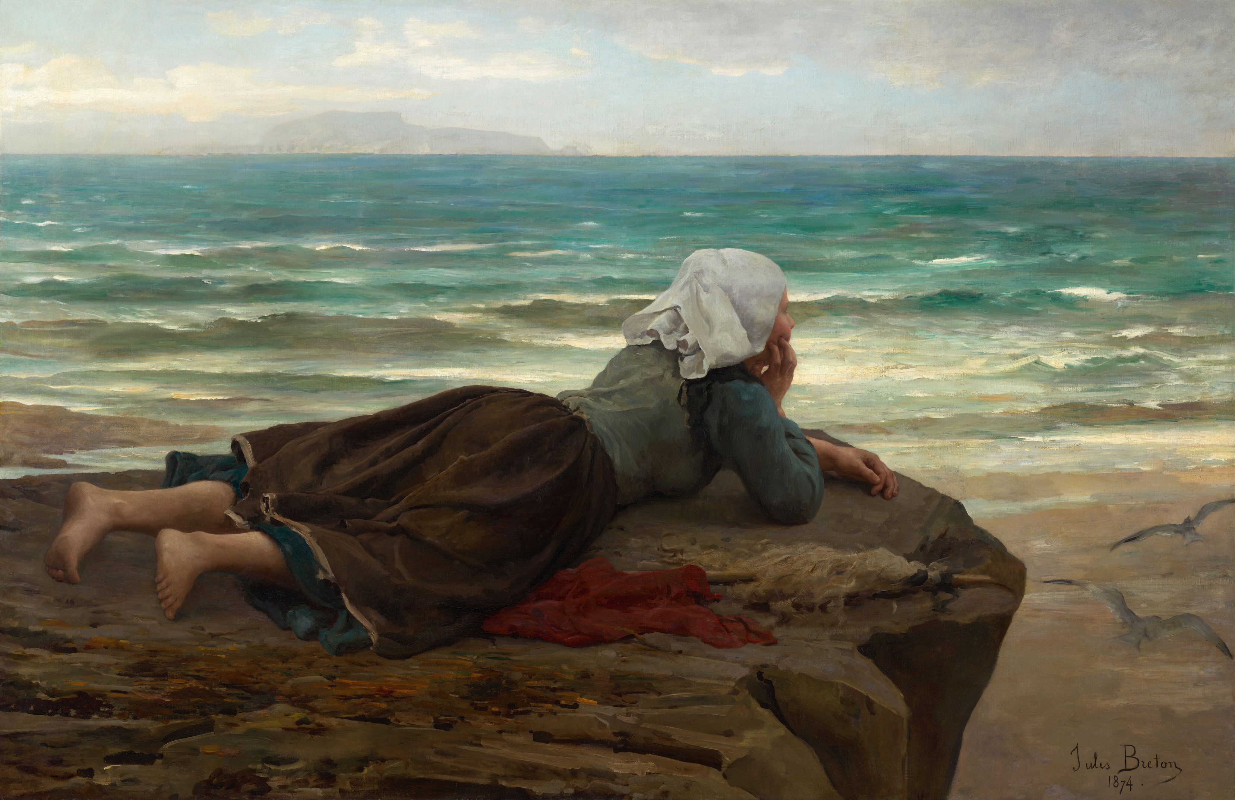 This painting shows a young woman lying on her stomach on a brown, rocky surface near the water's edge, looking towards the sea. The woman's bare feet are towards the bottom left corner of the painting, while her head is in the center, resting on her hand. She faces the right, and we see her back and side. She wears a pale green shirt with blue sleeves, a brown skirt, and a white cloth on her head. There is a red cloth on the ground next to her, as well as a pointed wooden stick that appears to be covered in white strips of cloth or feathers. The ground below her on the right is a tan, sandy color, and behind her is the sea, which is painted in vibrant turquoise and green shades, with white lines capping small waves. The sky is light blue with puffy white clouds, and distant landforms are visible in light gray across the water.