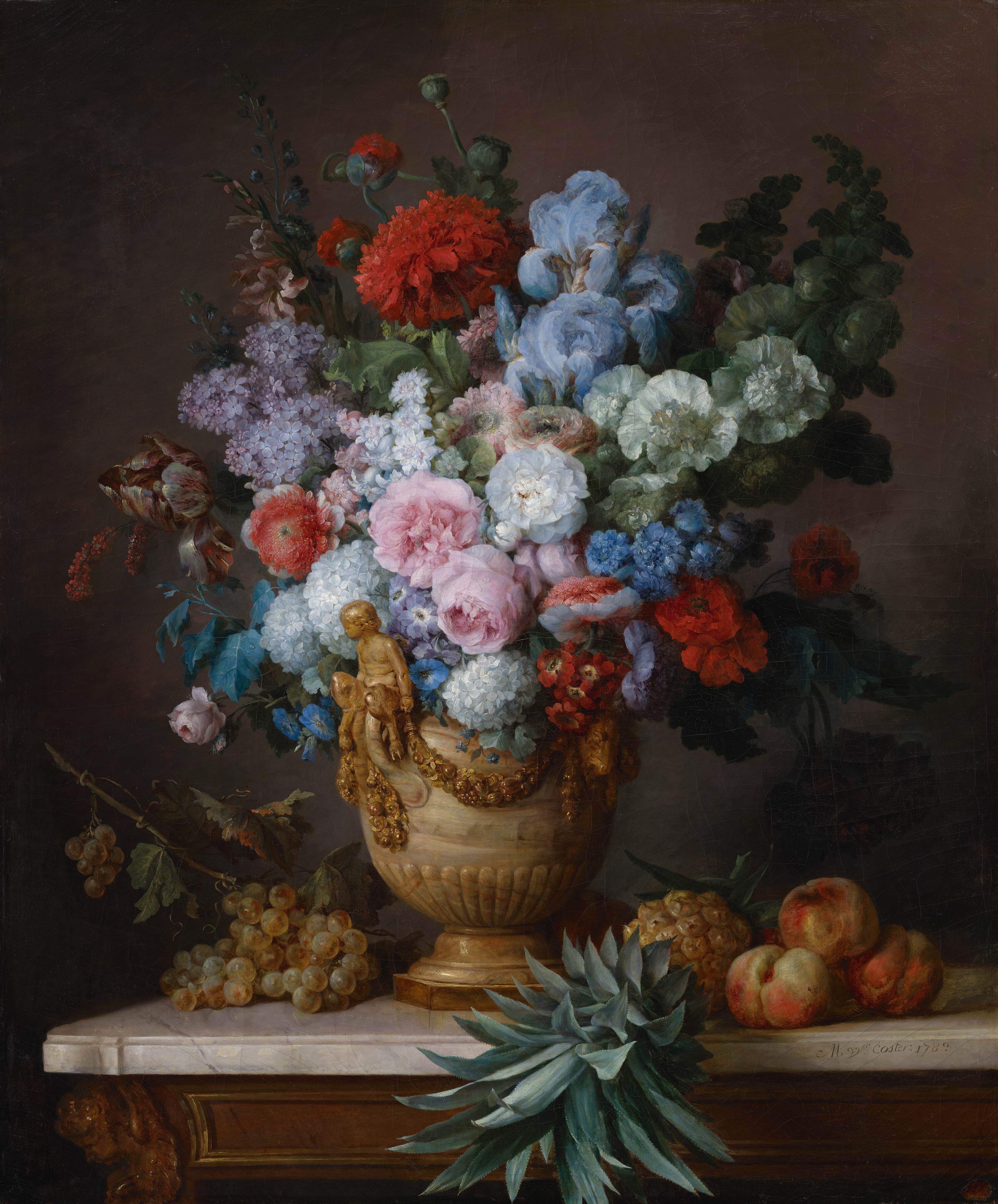 This painting features a large ornate vase overflowing with an arrangement of colorful flowers, including roses, peonies, and poppies. The color palette is vibrant and varied, with hues of red, pink, blue, purple, white, and green. Positioned in the center, the vase is adorned with gold embellishments, including a small carving of a person on its front. The vase stands on a marble surface that also holds a pineapple and peaches to the right. Several leaves and clusters of green grapes rest on the left side of the marble. The light source is at the upper left, illuminating the flowers and casting dark shadows behind them. The background of the painting is dark gray.
