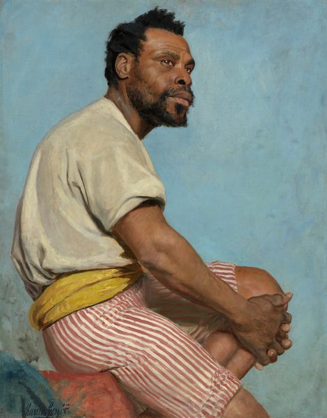 This painting shows a man seated with one knee bent, his body turned to the right and his face turned slightly back toward us. He has brown skin, high cheekbones, a short, curly black beard, and short black hair. His facial expression is neutral, and he is gazing off into the distance, his brown eyes turned slightly upwards. The man is wearing a cream-colored shirt with short sleeves, red and white striped shorts that end above his knees, and a yellow sash around his waist. His hands are clasped together on his bent knee, the other leg hanging downwards. The background is a solid light blue color with visible brushstrokes, and the man appears to sit on a red object in the bottom left corner, with a piece of blue fabric hanging off of it or in front of it.