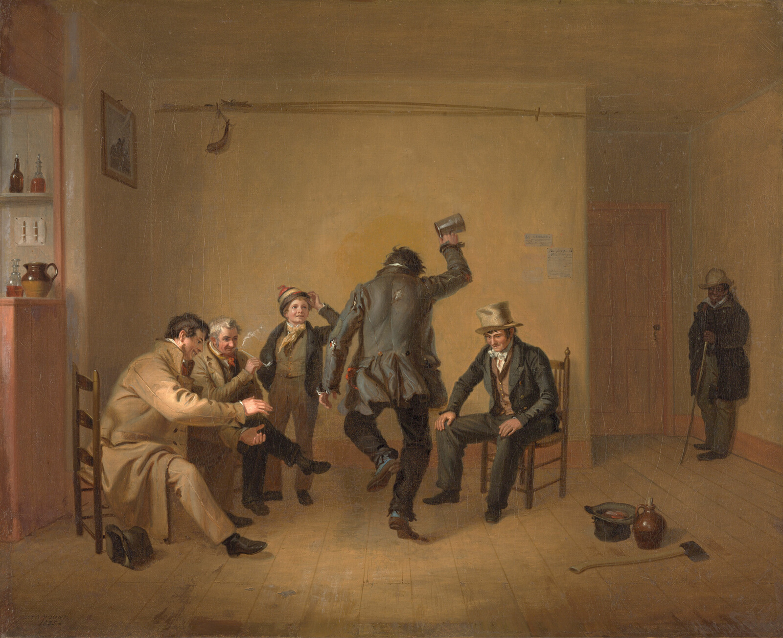 In a beige room, a group of light-skinned men of various ages and a young boy clap as a figure in tattered clothing at center, his back to the viewer, dances and holds a tin cup in the air. At dark figure in shadows looks on from the far-right corner.