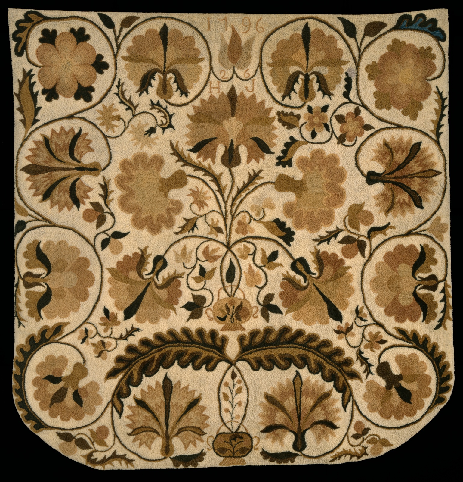 Large tan rug with black and brown floral motif.