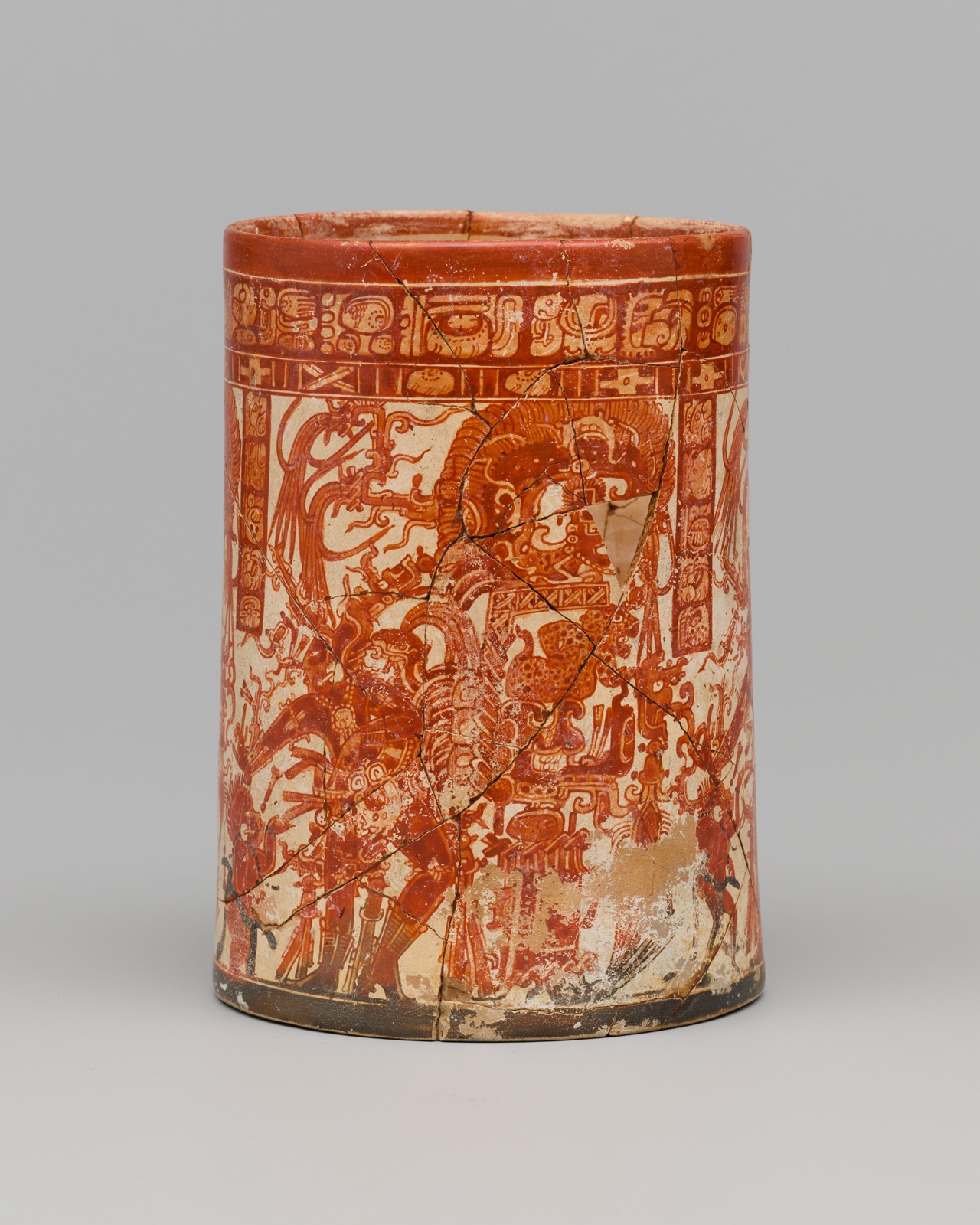 Cup shaped ceramic vessel with red glyphs and dancing figures, orange on cream ground.